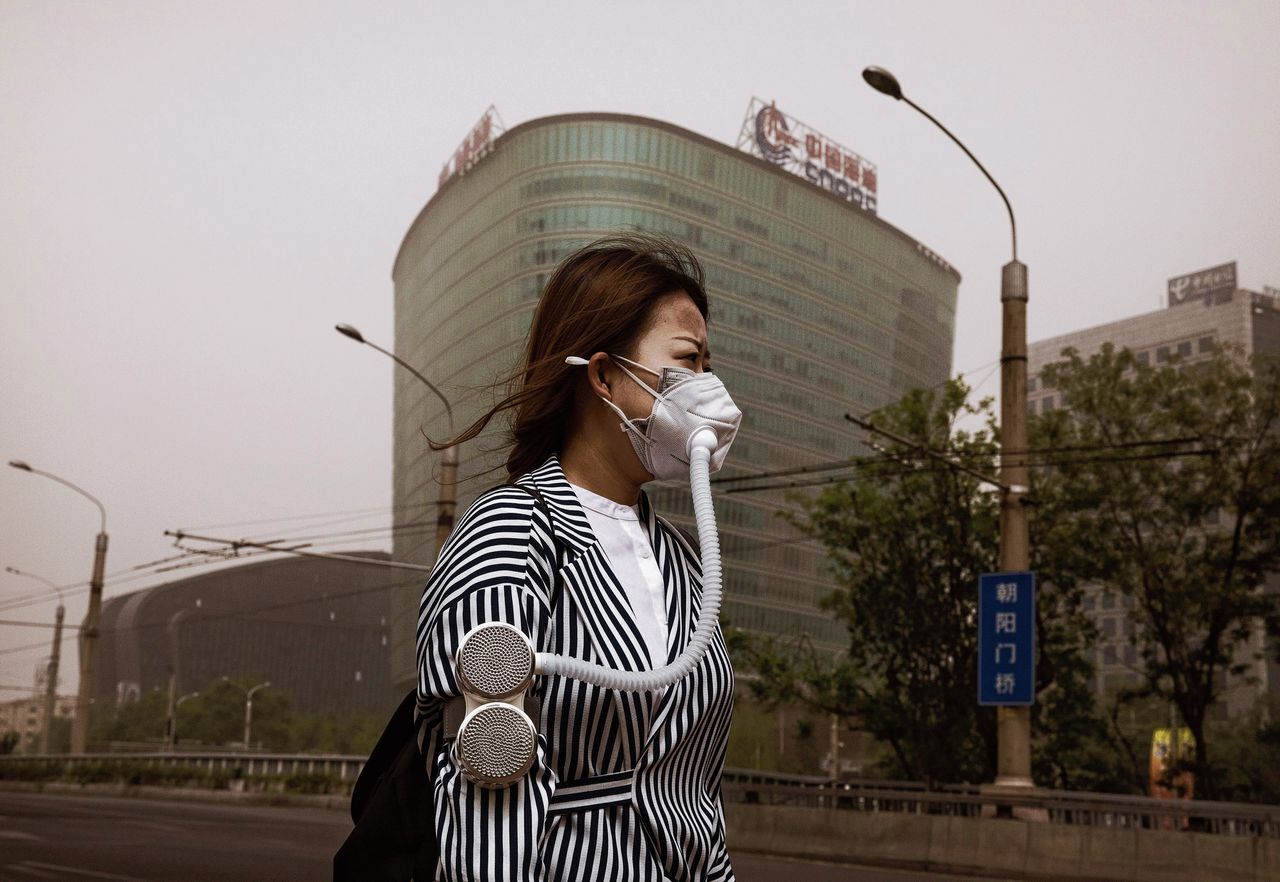Een vrouw in Beijing draagt een mondkapje, zoals zoveel Chinezen, vanwege de ernstige luchtvervuiling in China.