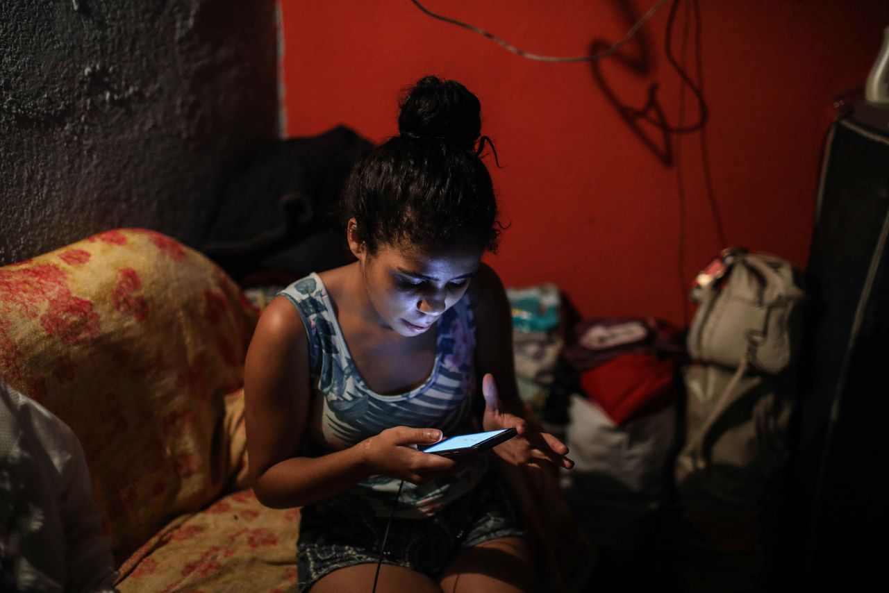 Andréa Silva de Souza, zoekt op haar telefoon naar foto’s van haar aan Covid-19 overleden dochtertje Vitoria.