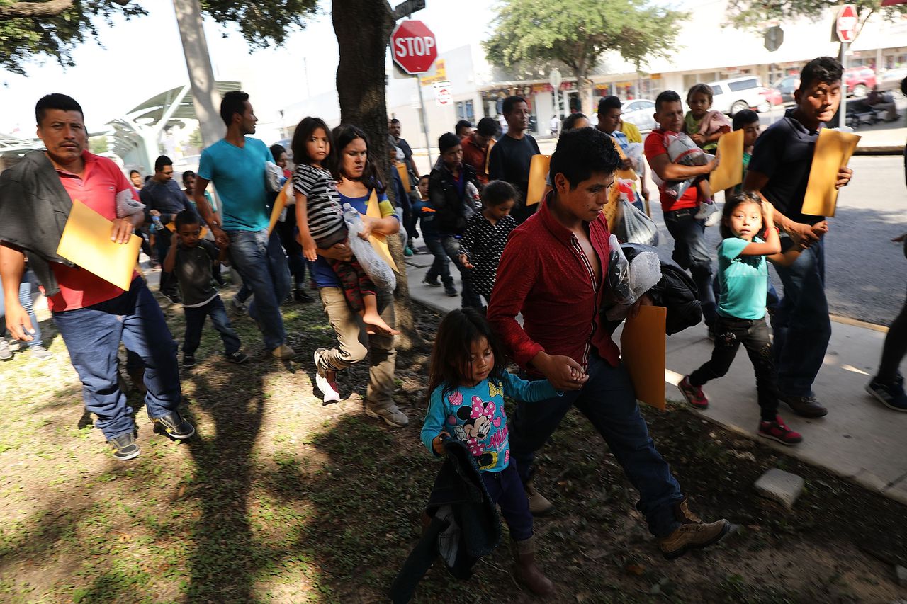 Mannen, vrouwen en kinderen komen aan bij een busstation nadat zij langs de douane en grensbescherming zijn geweest, beeld van zaterdag 23 juni.