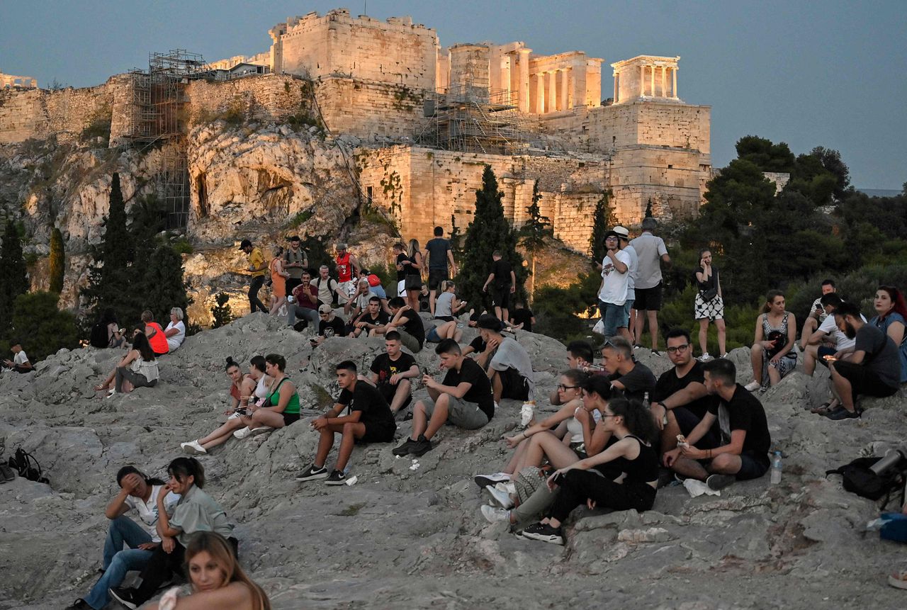 Mensen genieten van het uitzicht op de Acropolis in het Griekse Athene. Sinds 24 juni is het in Griekenland niet meer verplicht om buiten een mondkapje te dragen.
