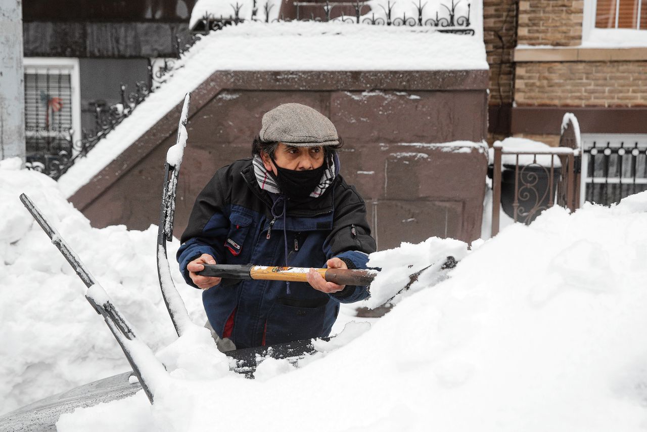 Een inwoner van New York maakt met blote handen zijn auto sneeuwvrij, afgelopen dinsdag.