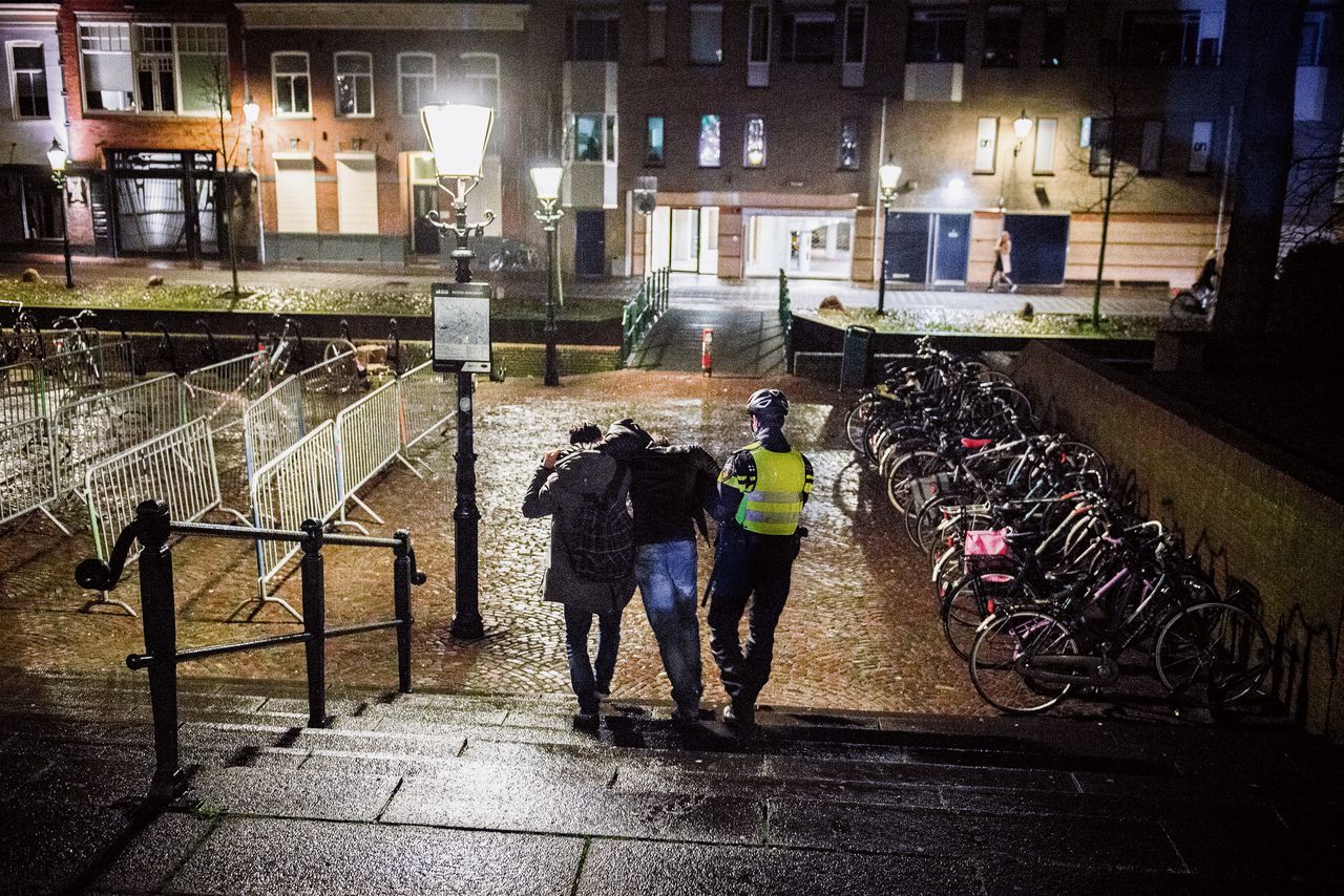 Een dronken jongen wordt door de politie ondersteund in de binnenstad van Amersfoort.