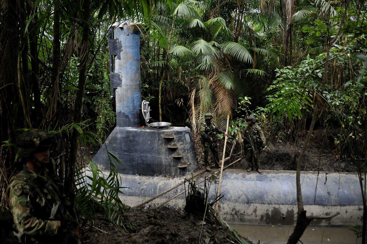 Colombian soldiers guard a homemade submersible in a rural area of Timbiqui, department of Cauca, Colombia, on February 14, 2011. A submersible with a capacity to transport up to 8 tons of cocaine with a sailing range from Colombia to Mexico was found on the southwestern coast of the Colombian Pacific Ocean, the Colombian Army said. AFP PHOTO/Luis Robayo
