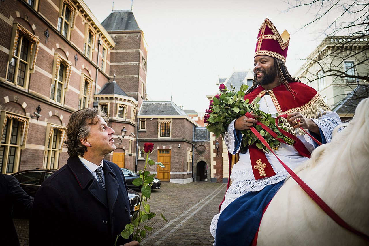 Patrick Mathurin deelt rozen uit op het Haagse Binnenhof. De in Haïti geboren Amsterdammer noemt zichzelf „niet de Zwarte Sint, maar Nieuwe Sint”.