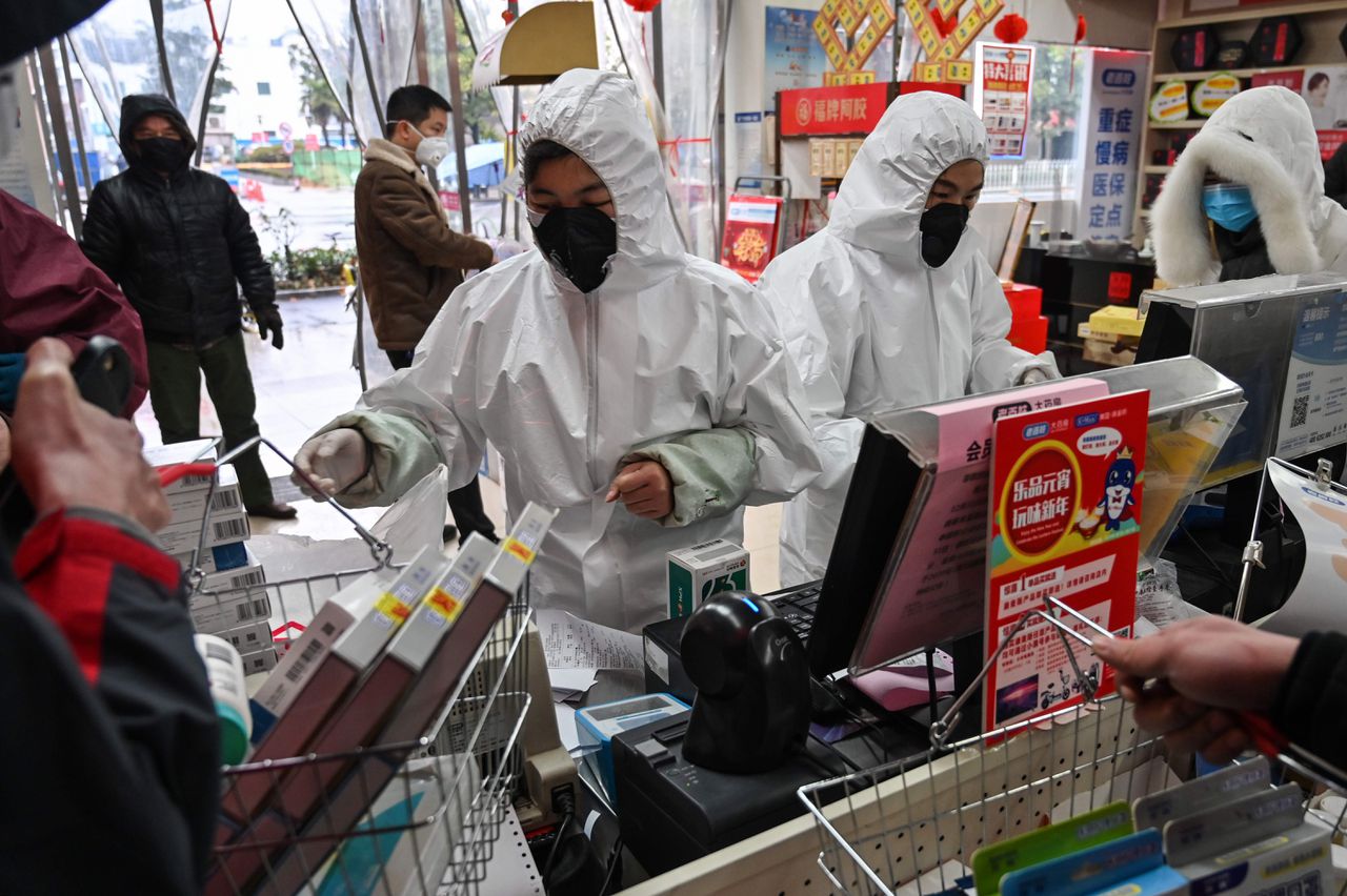 Medewerkers van een apotheek in de Chinese stad Wuhan, gehuld in beschermende kleding en mondkapjes, bedienen zaterdag klanten.