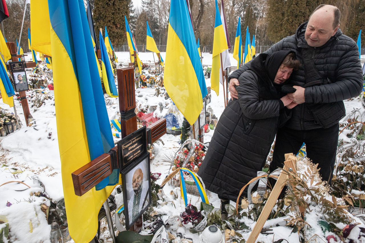 De ouders van overleden soldaat Andriy Shandra huilen samen bij zijn graf.
