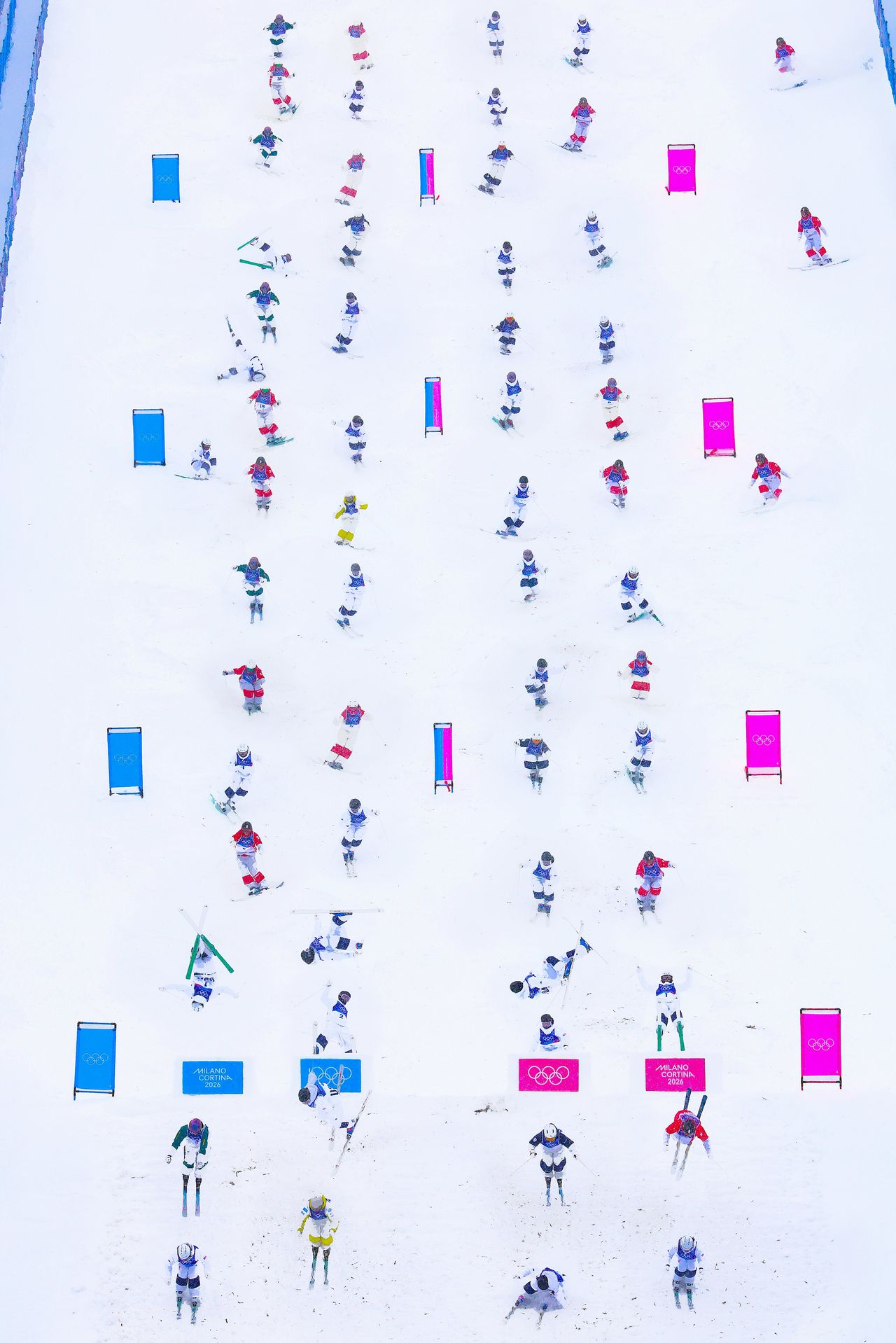 Beeld van het dual mogulskiën voor vrouwen, waarbij twee skiërs een piste vol hobbels (‘moguls’) afgaan én onderweg zo stijlvol mogelijk van twee schansen springen.