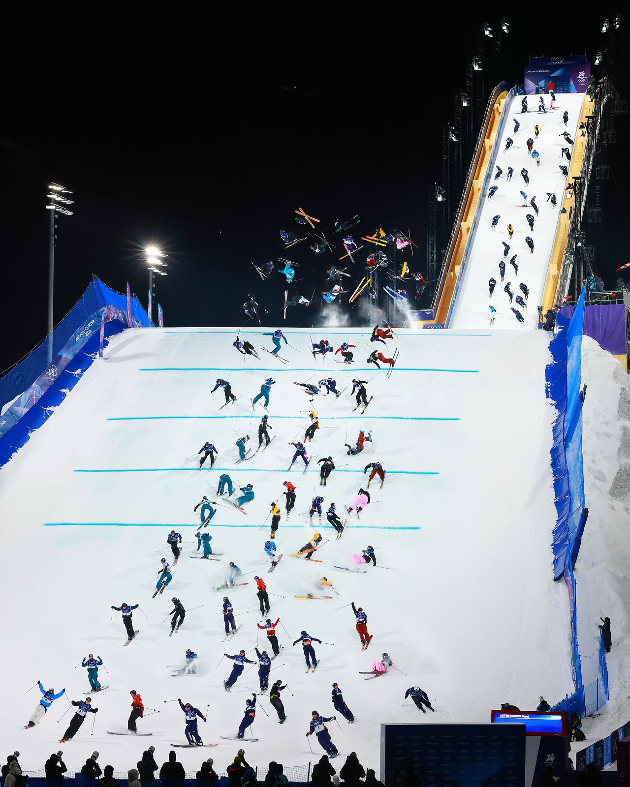 Beeld van de kwalificatie van het big air freestyle-skiën voor de mannen, waarbij skiërs van een grote schans springen en trucs in de lucht doen.
