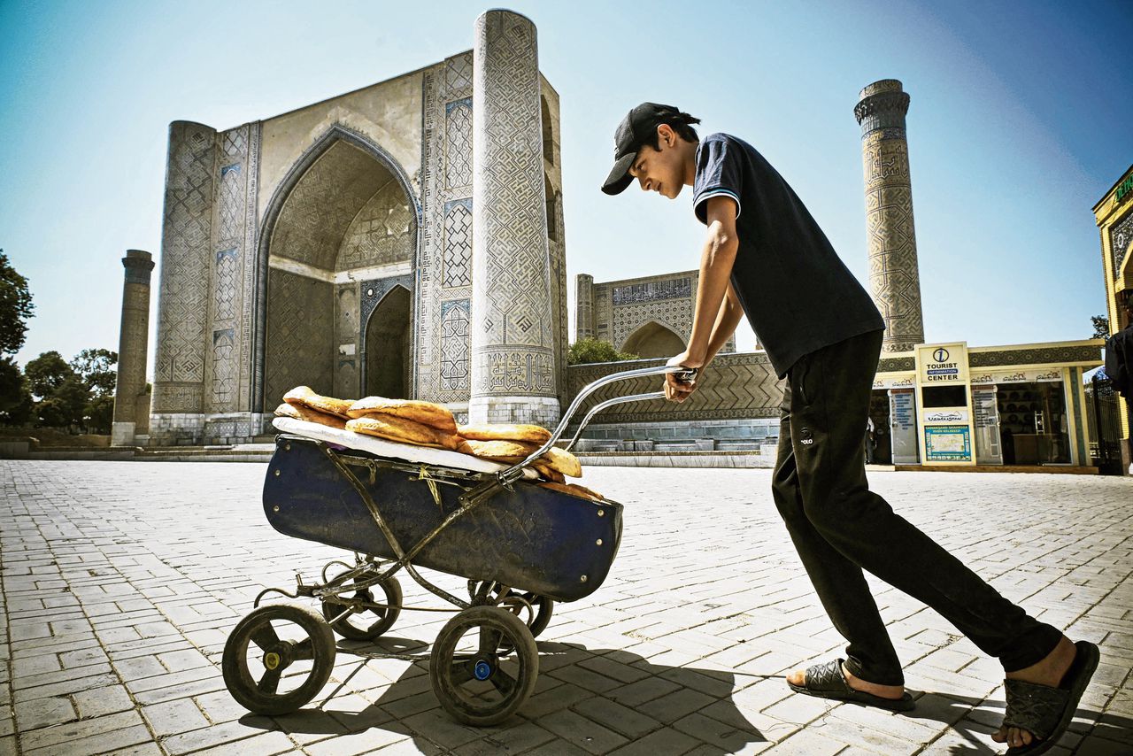 Een jongen vervoert vers brood bij de Bibi-Khanum moskee in het centrum van Samarkand, Oezbekistan.