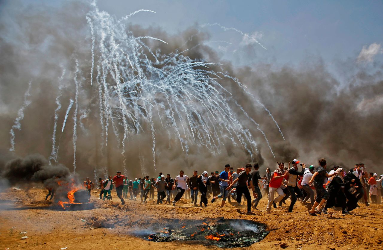 Palestijnse demonstranten zoeken dekking voor traangas, die door het Israëlische leger wordt afgeschoten.