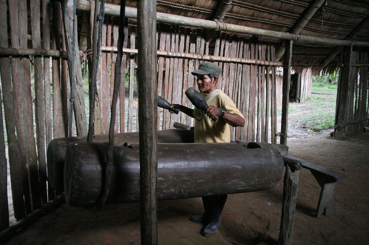 Lid van de Bora, een volk in het Peruaanse deel van het Amazonegebied, bespeelt een inheemse drum.