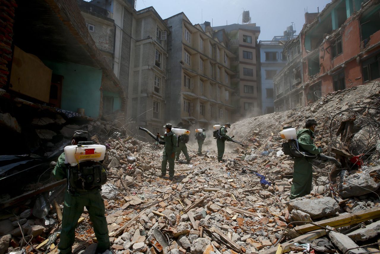 Chinese reddingswerkers desinfecteren het puin in de stad Kathmandu in Nepal.