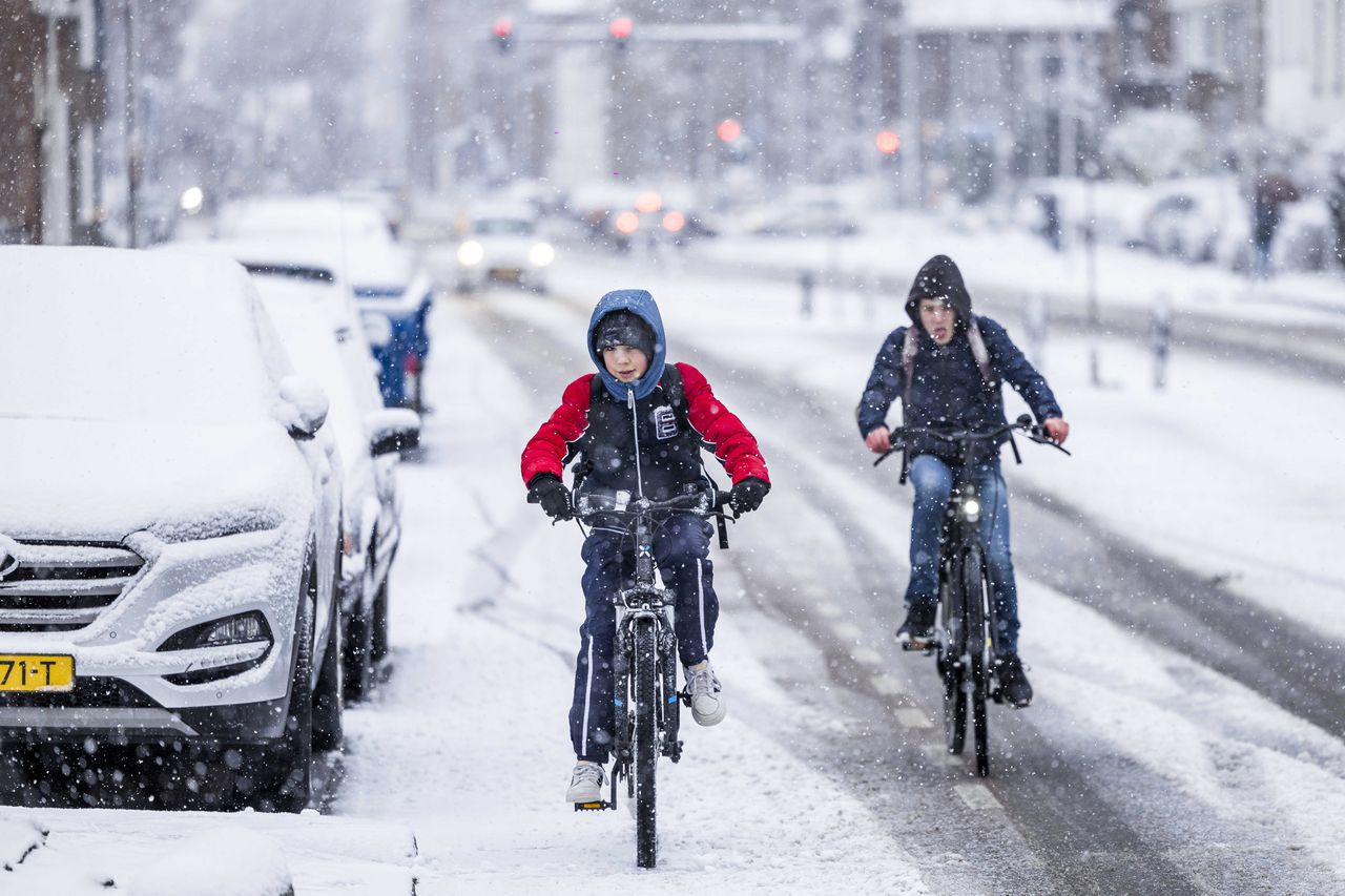 Kinderen fietsen naar school in de sneeuw in Heerlen.