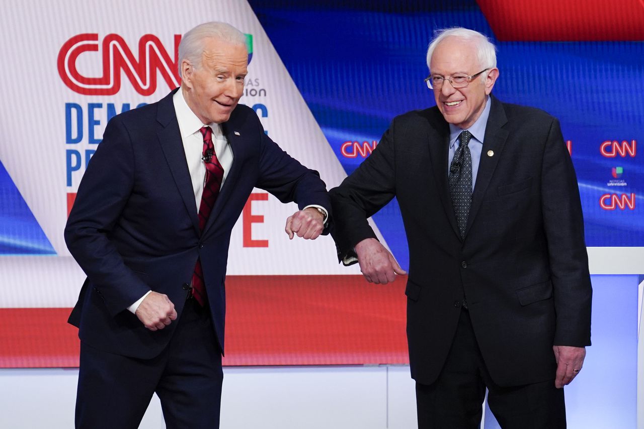 Oud-vicepresident Joe Biden (links) en senator Bernie Sanders begroeten elkaar zondagavond met hun ellebogen, voor hun verkiezingsdebat in Washington.