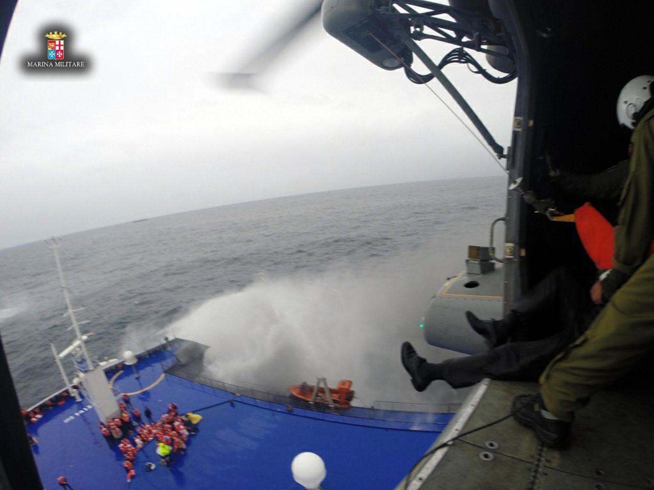 De Italiaanse marine haalt met helikopters mensen van de veerboot. De weersomstandigheden zijn ruw op zee.