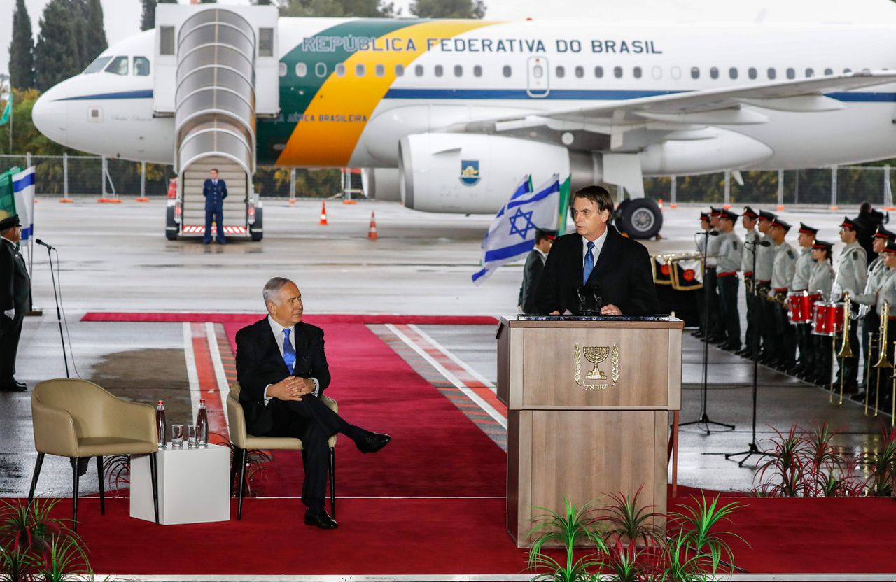 De Israëlische premier Benjamin Netanyahu (links) luistert zondag op de luchthaven van Tel Aviv naar de net gearriveerde Braziliaanse president Jair Bolsonaro.