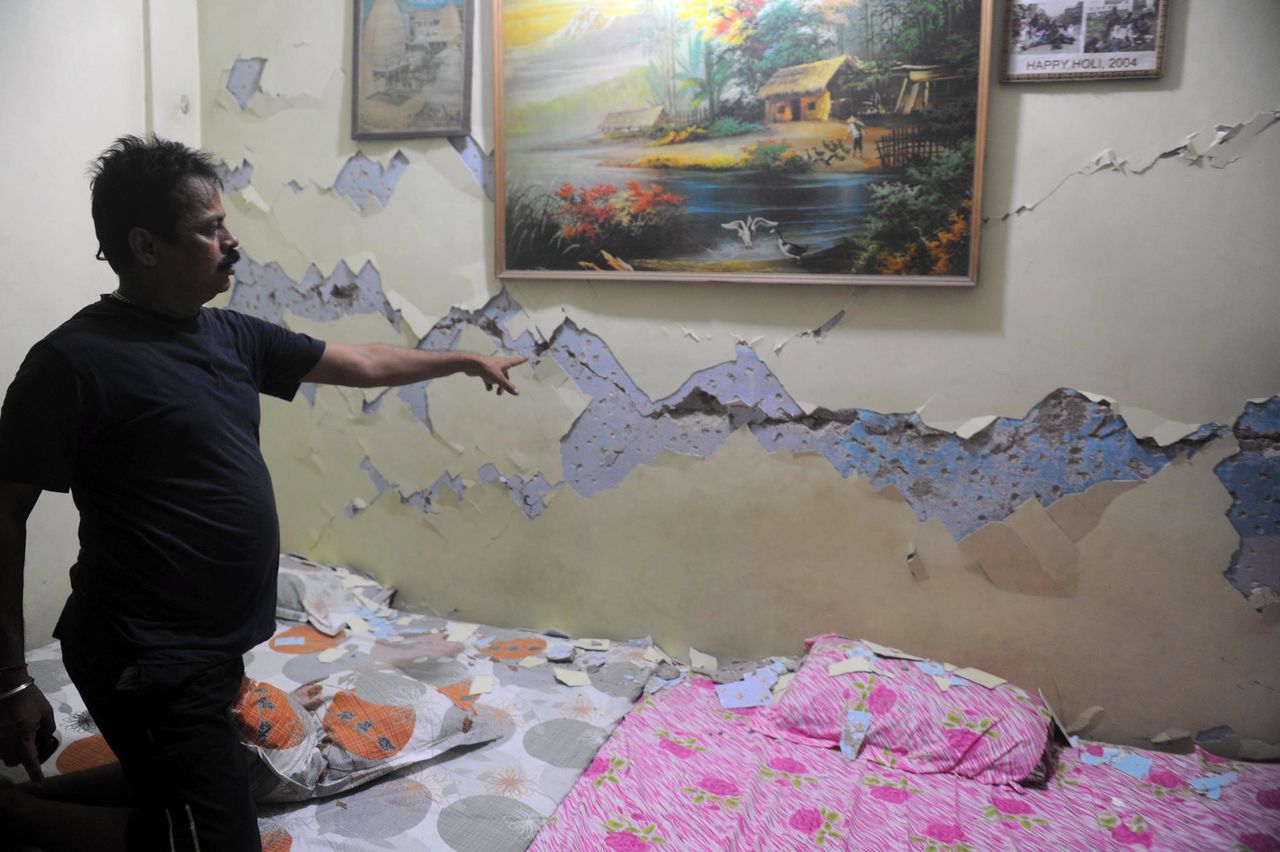 Een Indiase man laat zien dat de aardbeving van vandaag een scheur in zijn muur veroorzaakte.