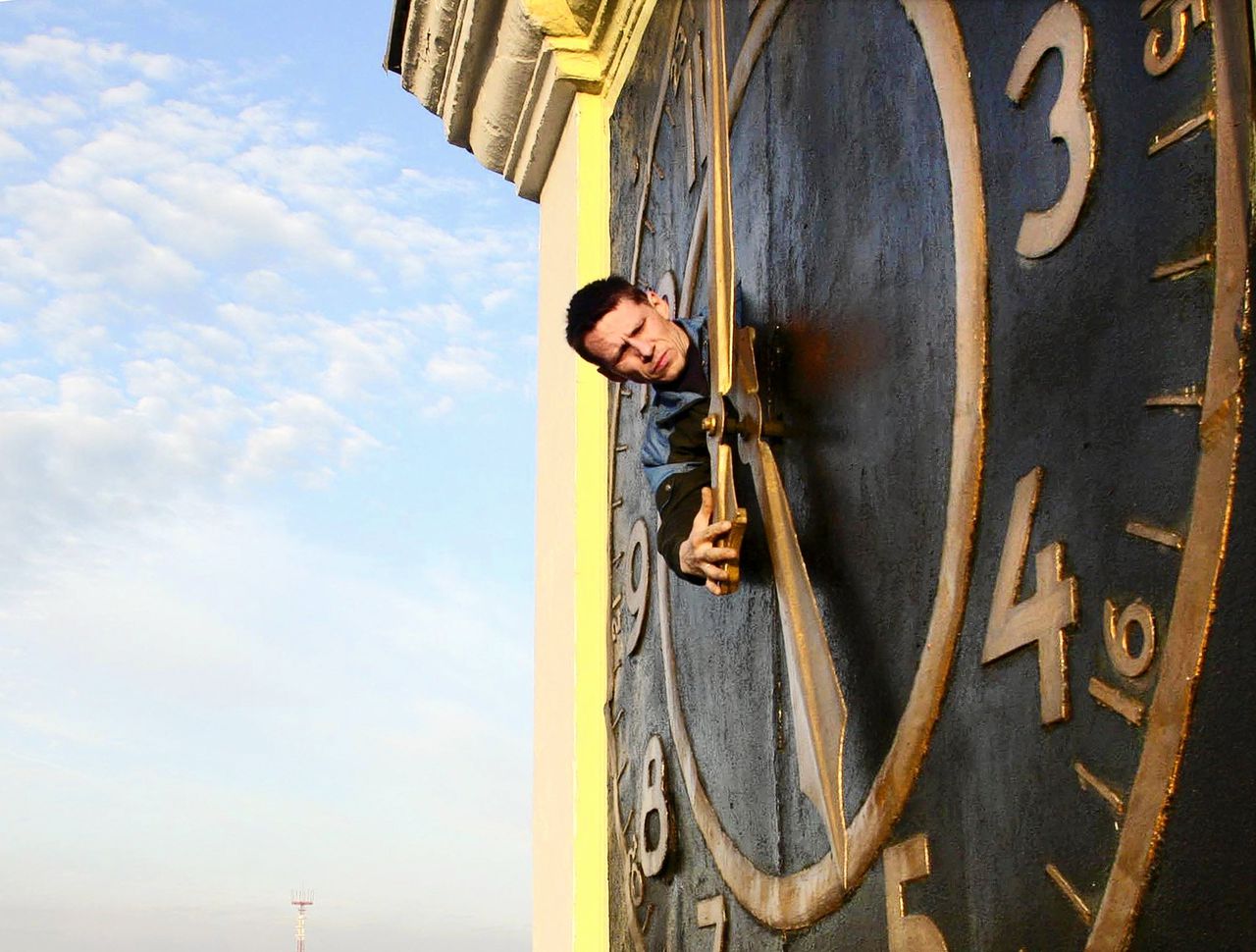 Een gemeentemedewerker stelt een klok in het centrum van Minsk bij na de ingang van de wintertijd.