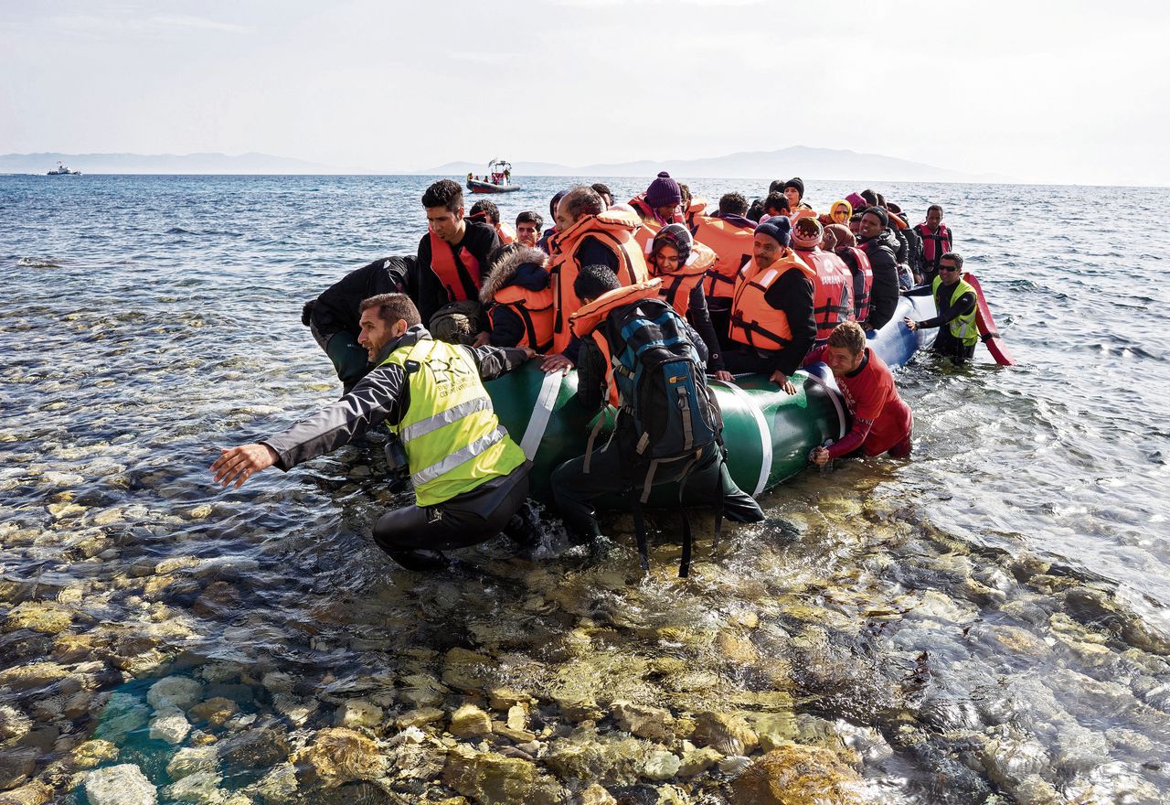 Leden van ERCI trekken een boot met migranten aan land op het Griekse eiland Lesbos.