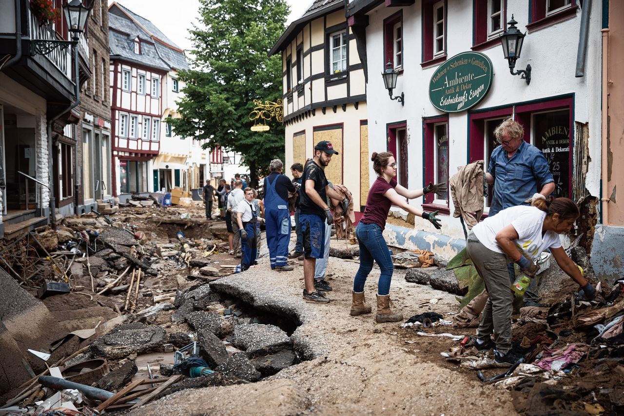 In Bad Münstereifel vormen mensen een doorgeefketting om handmatig het puin uit de straat te krijgen, omdat ze er niet met een kruiwagen kunnen rijden.