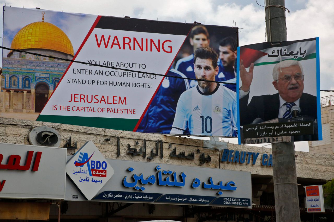 Een poster met Lionel Messi hangt naast een portret van de Palestijnse president Abbas.