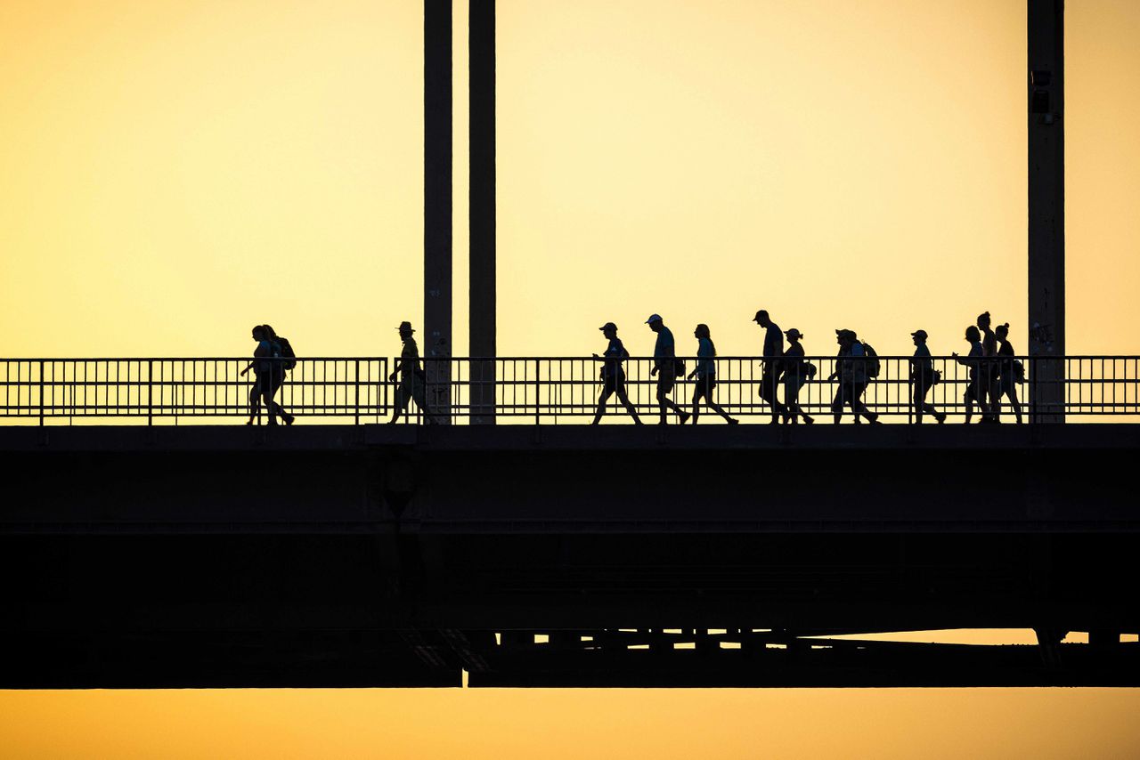 Wandelaars tijdens zonsopgang dinsdag bij De Waalbrug in Nijmegen.