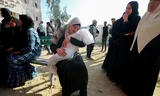 A Palestinian woman holds the body of a child, killed by an Israeli bombing in North Gaza on April 28. Photo Mahmoud Issa 