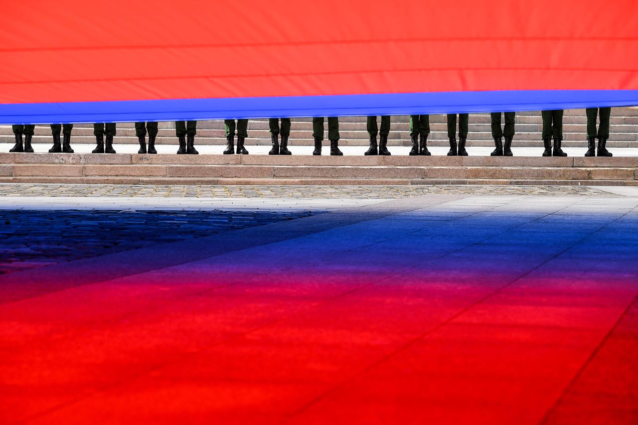 Russische militairen houden een grote Russische vlag vast op de Nationale Vlaggendag op 22 augustus.