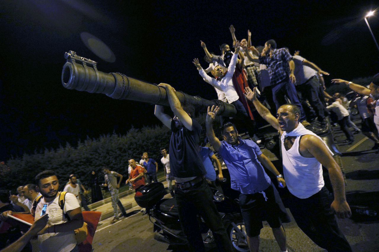Mensen staan op een tank van het leger op het vliegveld Ataturk in Istanbul.