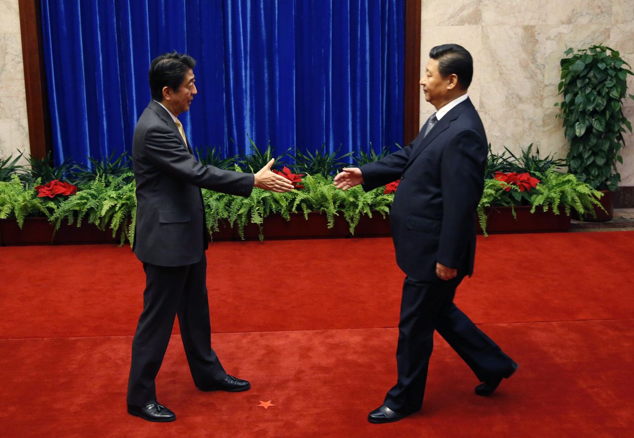 De Japanse premier Shinzo Abe (links) staat op het punt de hand van de Chinese president Xi Jinping te schudden.