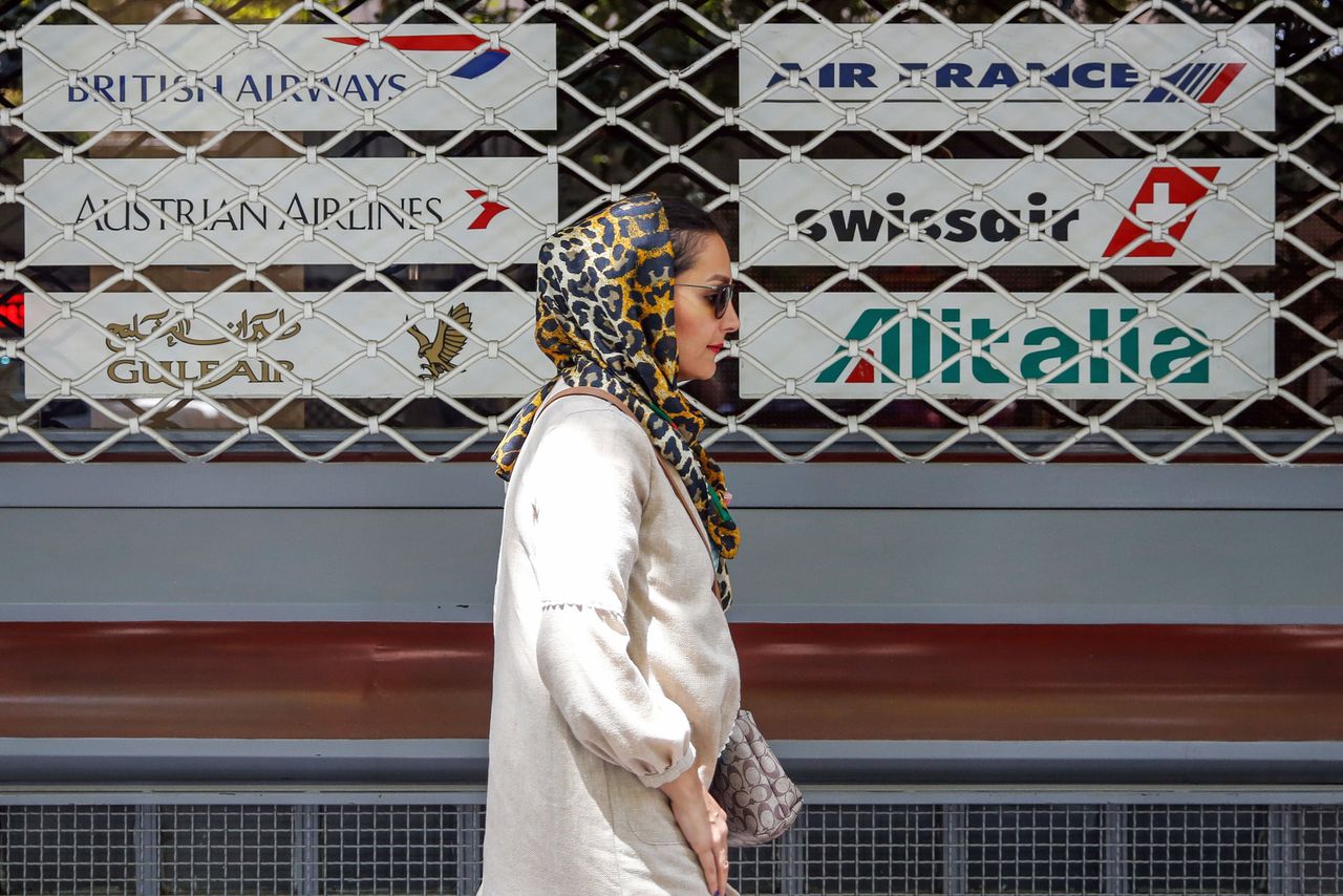Een Iraanse loopt langs een gesloten reisbureau in Teheran. Als gevolg van de Amerikaanse sancties tegen het land kondigden verscheidene Europese luchtvaartmaatschappijen, waaronder KLM, aan hun lijndiensten naar Teheran te staken. Zondagnacht worden nieuwe Amerikaanse sancties van kracht.