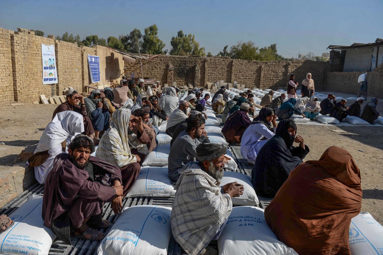 Afghanen in Kandahar zitten naast door het Wereldvoedselprogramma van de VN uitgedeelde voedselhulp.