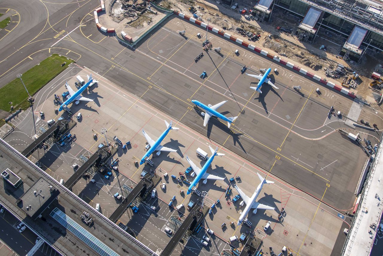 Luchtfoto van geparkeerde vliegtuigen bij de gate op luchthaven Schiphol.