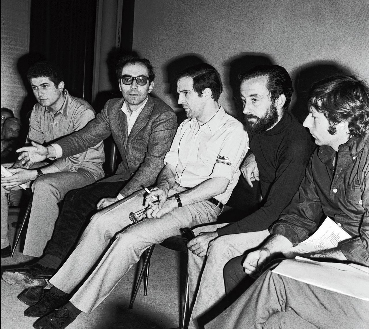 Jean-Luc Godard (tweede van links, met bril) met andere regisseurs tijdens een persconferentie op het Filmfestival van Cannes, in mei 1968. Links van Godard zit Claude Lelouch, rechts van hem zitten François Truffaut, Louis Malle en Roman Polanski.
