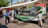 Voor de kraam van de GNSV in Leiden heeft een activist een emmer vuiligheid gedeponeerd. Vandaar dit schoonmaken. Foto Walter Herfst