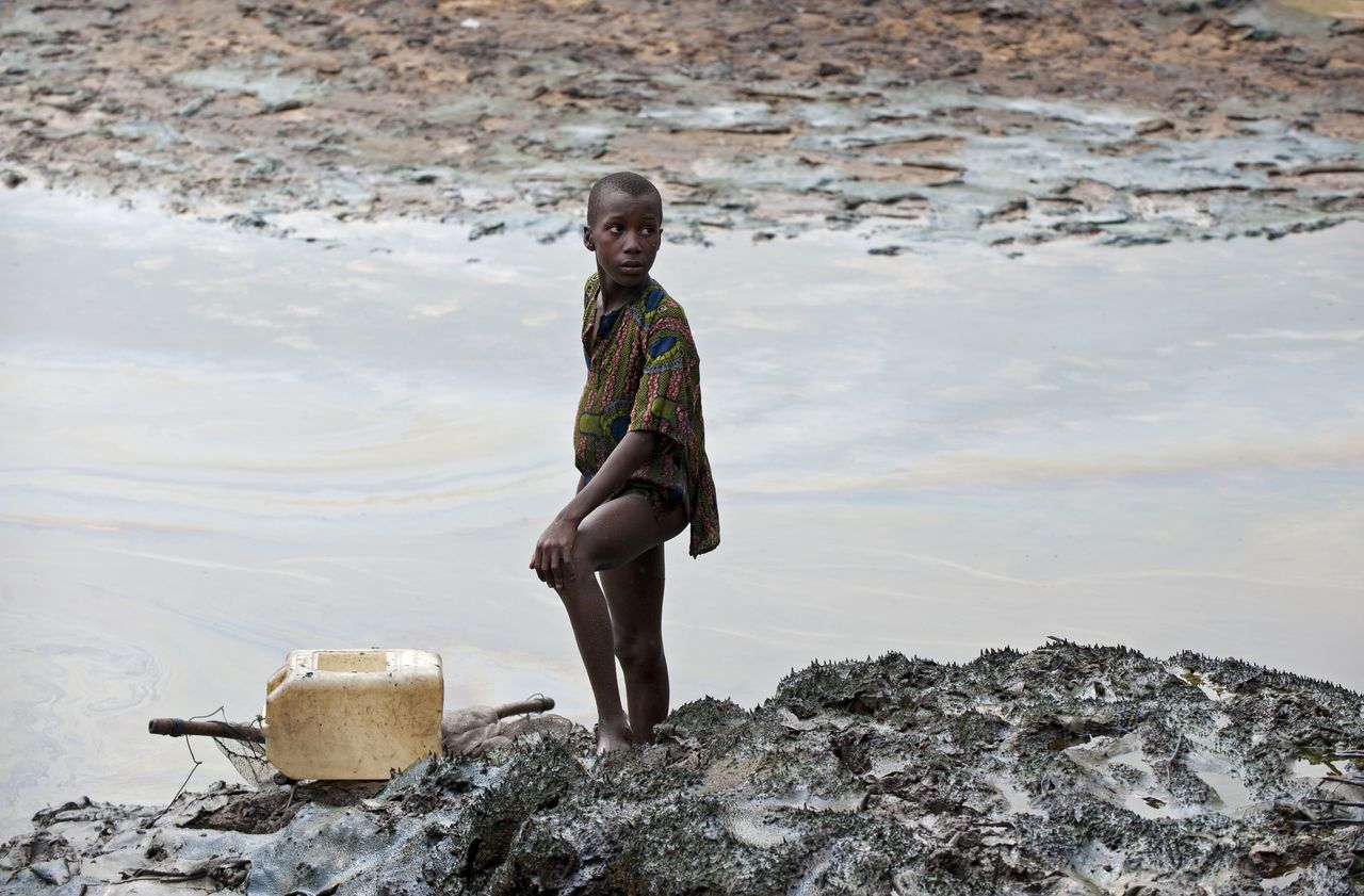 Een jongen in een door olielekkages zwaar vervuilde rivierslenk in Ogoniland, op archiefbeeld uit 2013.