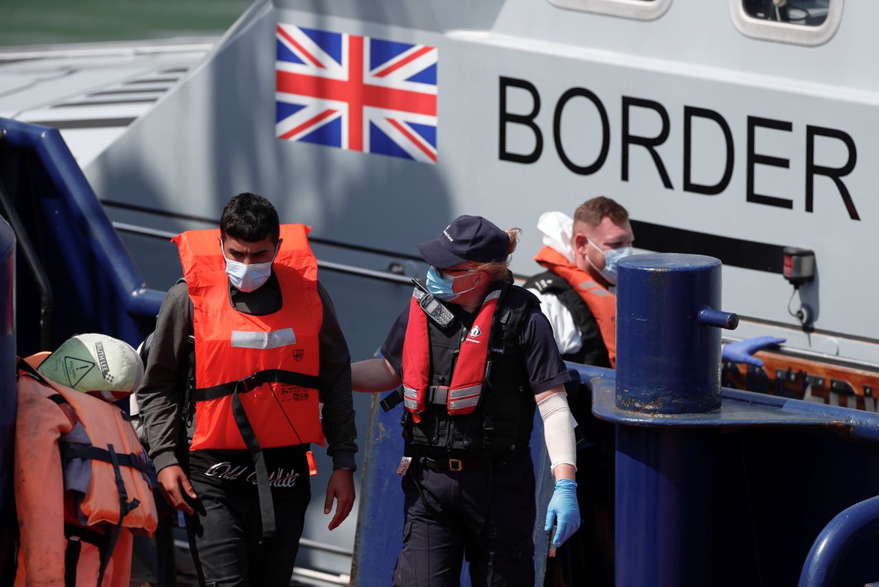 Een migrant wordt door de kustwacht van boord geholpen in de haven van Dover.
