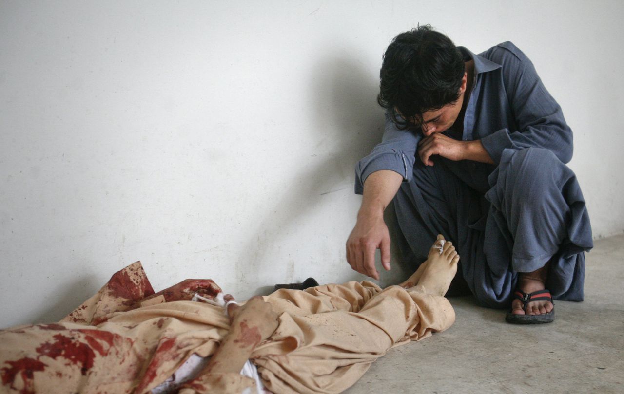 Een man rouwt bij het lichaam van zijn elfjarige broertje na een bomaanslag met een auto in Quetta, Pakistan, vandaag.