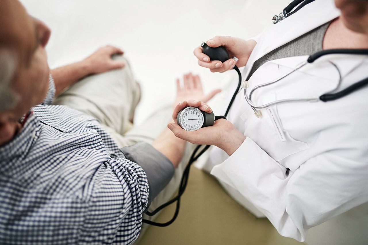 Een huisarts meet de bloeddruk van een patiënt.