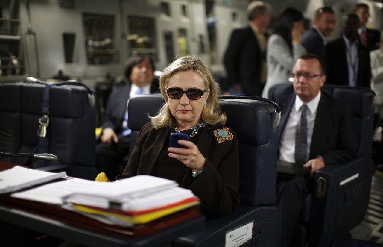 Clinton in 2011 als minister van Buitenlandse Zaken checkt haar Blackberry aan boord van een militair vliegtuig op weg naar Tripoli.