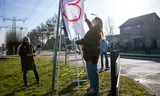 Suzie Klapwijk, organisator van de vredesmars, en een deelnemer hangen een spandoek met harttekening op tijdens de vredesmars tegen negatieve reacties op de voorgestelde locatie van een azc in Nieuw-Lekkerland.