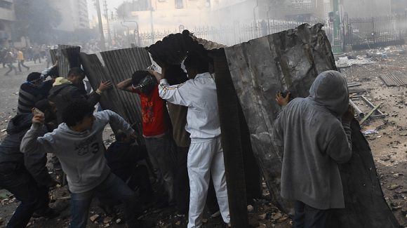 Caption: Protesters throw stones at army soldiers as they take cover at the cabinet near Tahrir Square in Cairo December 16, 2011. At least two people were killed and 100 wounded in Cairo on Friday as demonstrators fought troops in the worst violence since Egypt began its first free election in six decades. In a pattern that has recurred during nine months of army rule since President Hosni Mubarak's overthrow in February, the confrontation swiftly grew as more people took to the streets. REUTERS/Amr Abdallah Dalsh (EGYPT - Tags: CIVIL UNREST POLITICS)