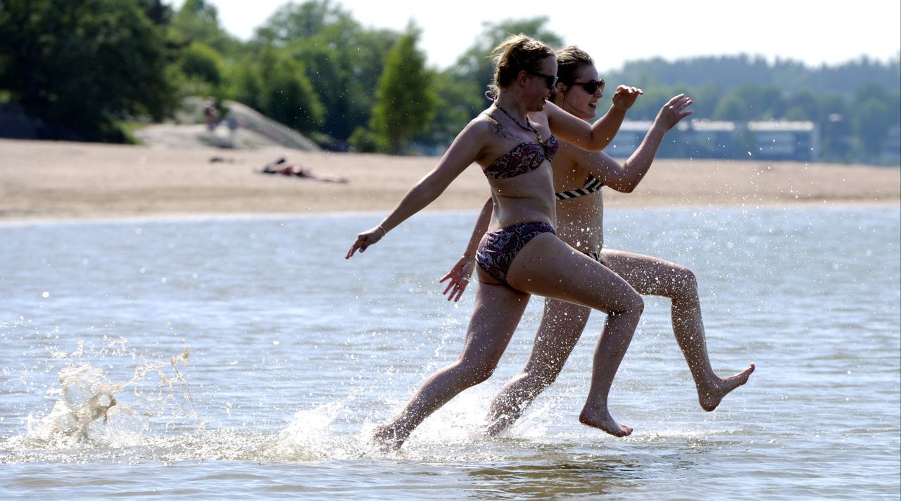 Senni Siltavuori (L) from Vantaa and Sanna Vakkilainen from Espoo take a dip to the sea at the Hietaniemi beach in Helsinki on May 31, 2013. As the most of the Europe suffers from cold weather and rain, Finns have been able to enjoy of plus 30 Celsius summer weather. AFP PHOTO / LEHTIKUVA / Jussi Nukari *** FINLAND OUT ***
