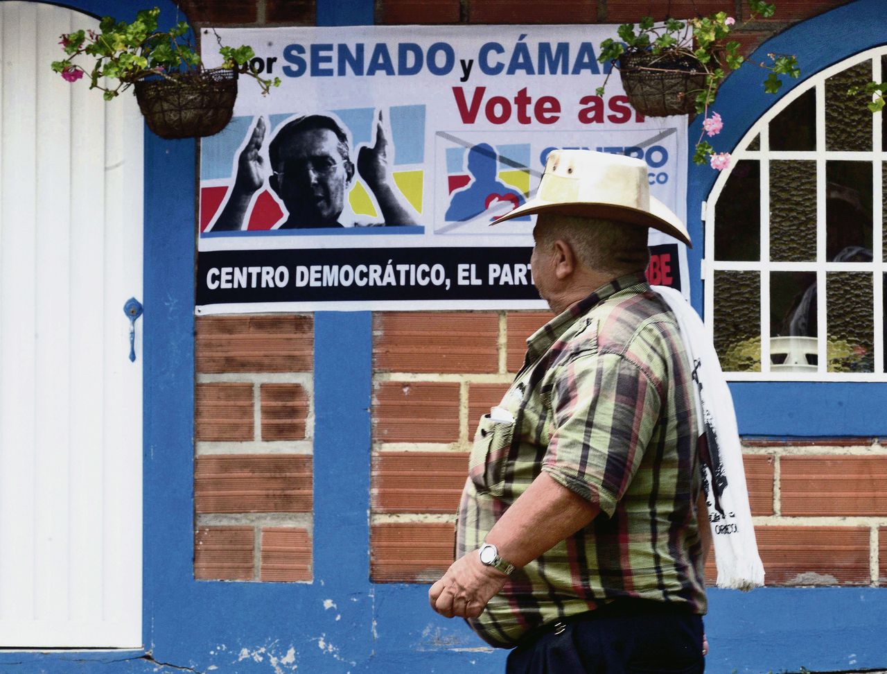 Een Colombiaan loopt langs een affiche van ex-president Uribe.