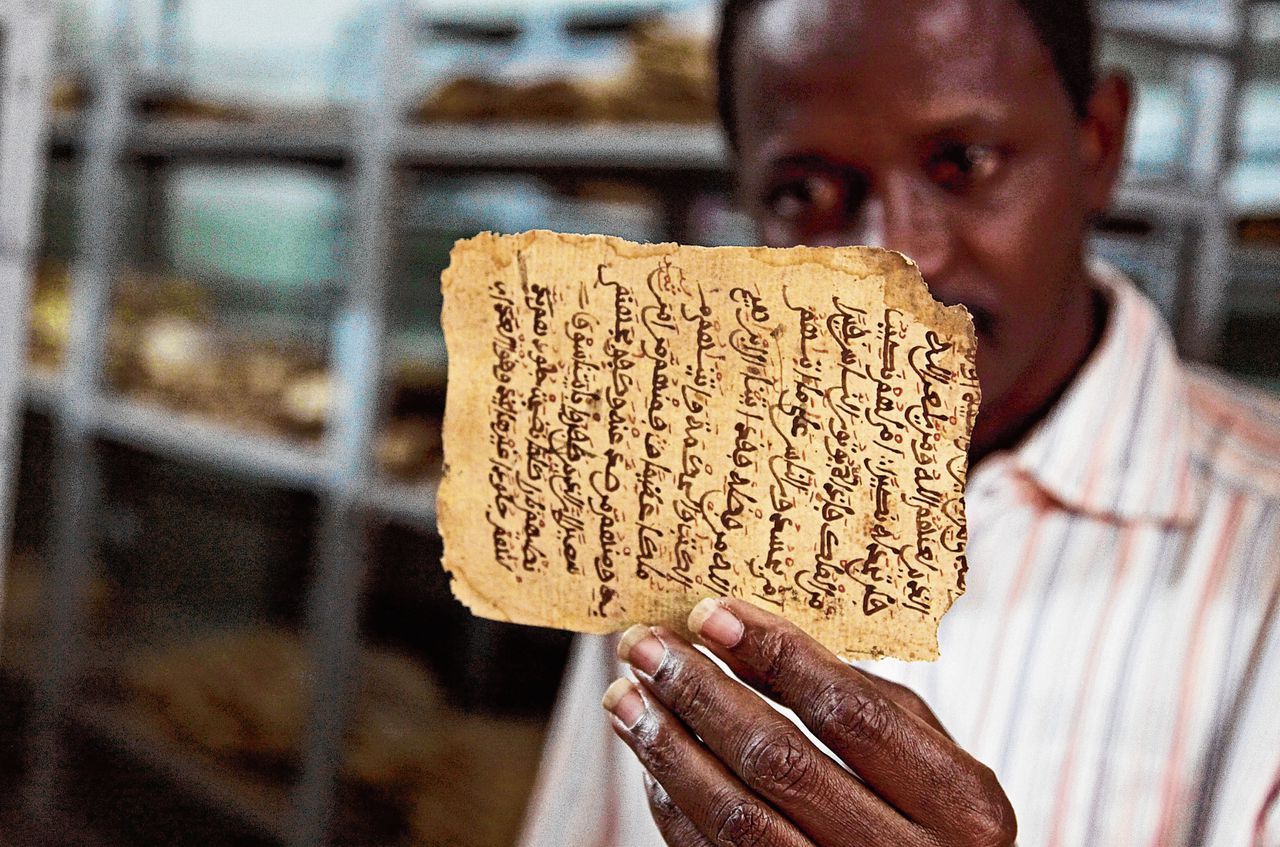 Een man in Bamako toont een beschadigd manuscript, begin 2015. Tijdens de jihadistische bezetting van Timboektoe werd gevreesd voor de eeuwenoude verzameling teksten. Met steun van het Nederlandse Prins Claus Fonds werden in 2012 in het geheim honderdduizenden manuscripten geëvacueerd.