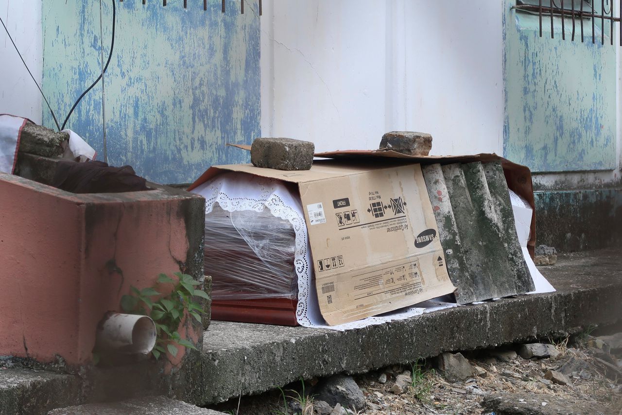 Een doodskist met daarin het lichaam van iemand die overleden zou zijn aan Covid-19 is provisorisch afgedekt en buiten een appartementencomplex in de Ecuadoraanse havenstad Guayaquil neergezet.