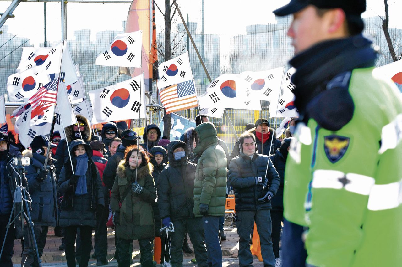 Zuid-Koreaanse toeschouwers protesteren in Incheon met vlaggetjes tegen het gemengde ijshockeyteam met speelsters uit zowel Noord- als Zuid-Korea.