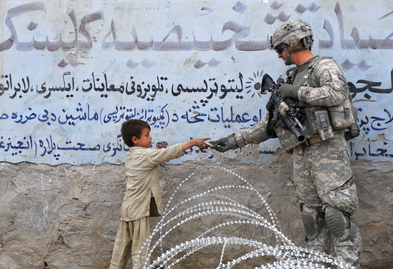 Een Amerikaanse militair geeft een Afghaanse jongen een cadeautje.