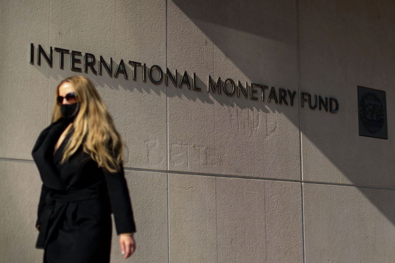 Een vrouw met mondkapje loopt langs het hoofdgebouw van het IMF in Washington DC.