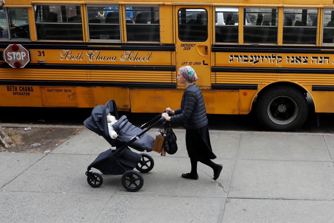 Een orthodox-joodse vrouw loopt langs een schoolbus. Dinsdag kondigde burgemeester Bill de Blasio extra maatregelen aan om de mazelenuitbraak te beheersen.